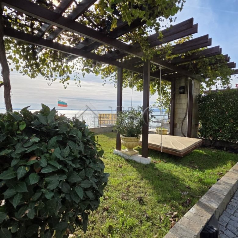 Sea view balcony of a 1-bedroom apartment in Sveti Vlas, Bulgaria, with outdoor seating and lush gre.