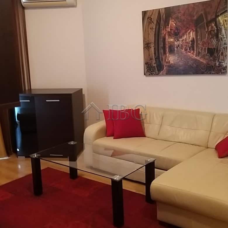Comfortable living room with cream sofa, red cushions, and wall art in a modern apartment.