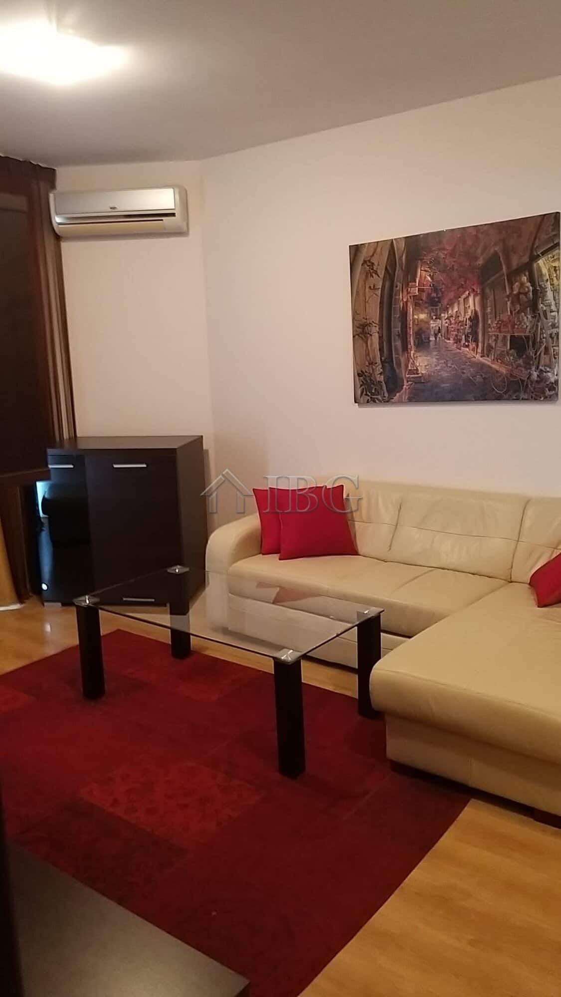 Comfortable living room with cream sofa, red cushions, and wall art in a modern apartment.