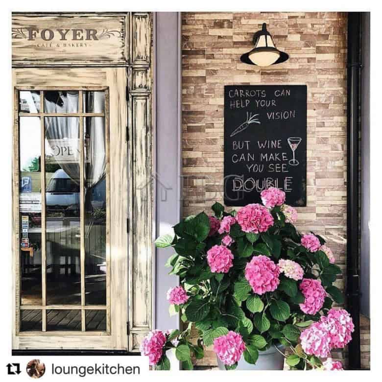 Inviting restaurant entrance featuring a rustic door and vibrant pink hydrangeas outside.