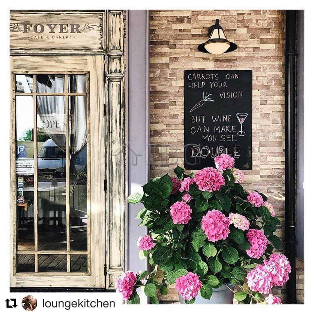 Inviting restaurant entrance featuring a rustic door and vibrant pink hydrangeas outside.