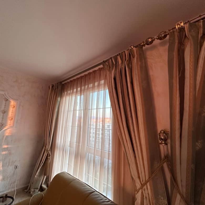 Bright living room with large windows and elegant curtains in Venera Palace, Sunny Beach.