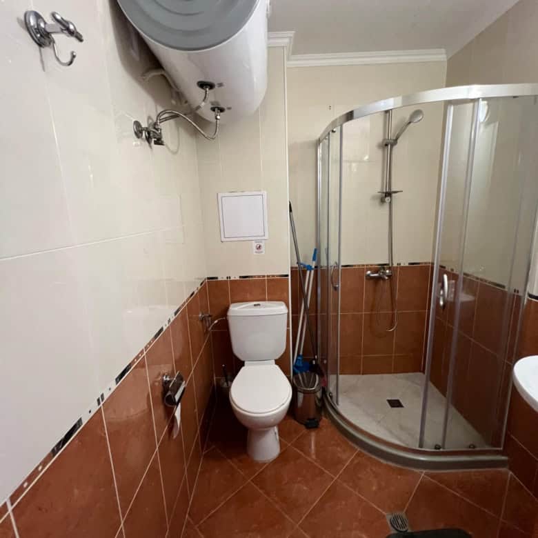 Bathroom with shower enclosure, toilet, and water heater in Diamant Complex, Sveti Vlas.