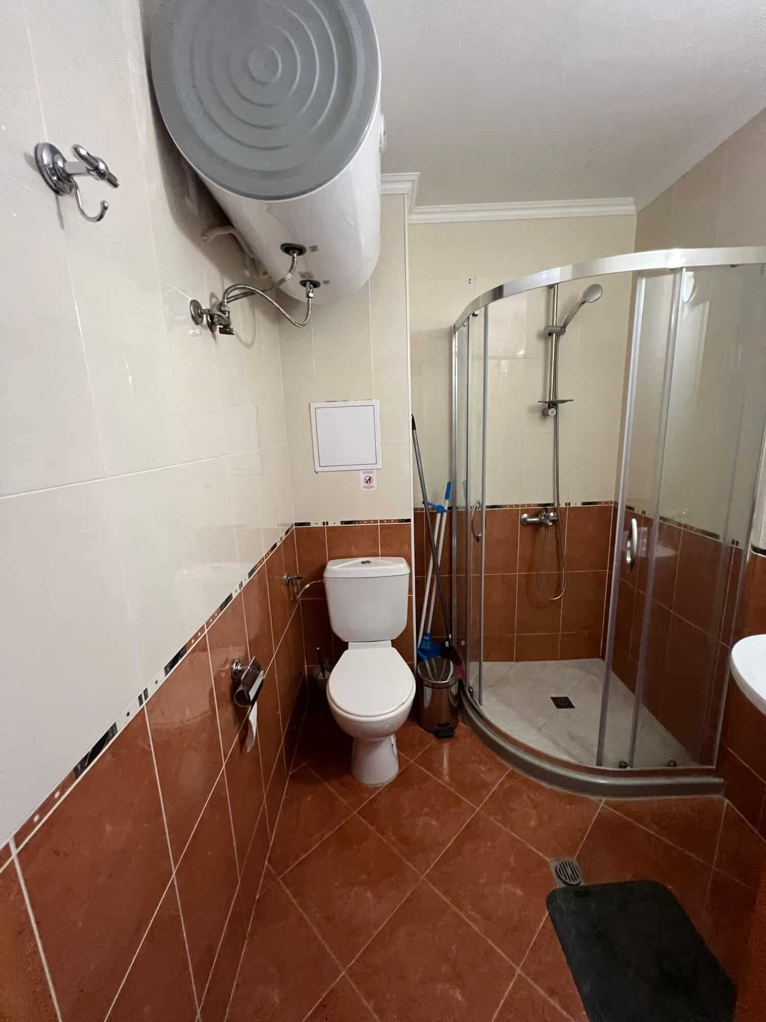 Bathroom with shower enclosure, toilet, and water heater in Diamant Complex, Sveti Vlas.