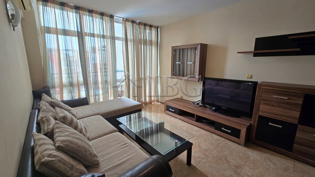 Bright living room with sofa, TV, and large windows in Sunny Beach apartment.