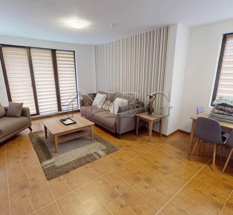 Spacious living room with large windows and cozy sofas in Bay View Villas, Kosharitsa.