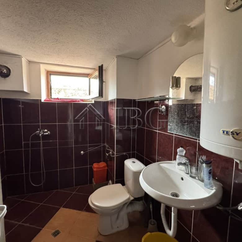 Modern bathroom with shower, toilet, and sink in Kosharitsa property. Bright window offers natural l.