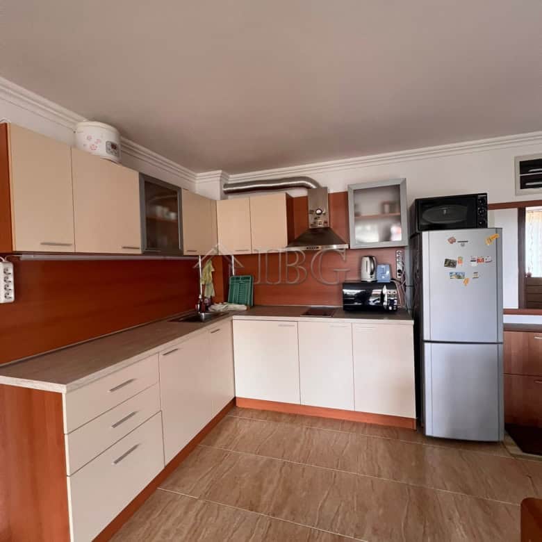 Spacious kitchen with white and wood cabinets, refrigerator, and appliances in Sveti Vlas.