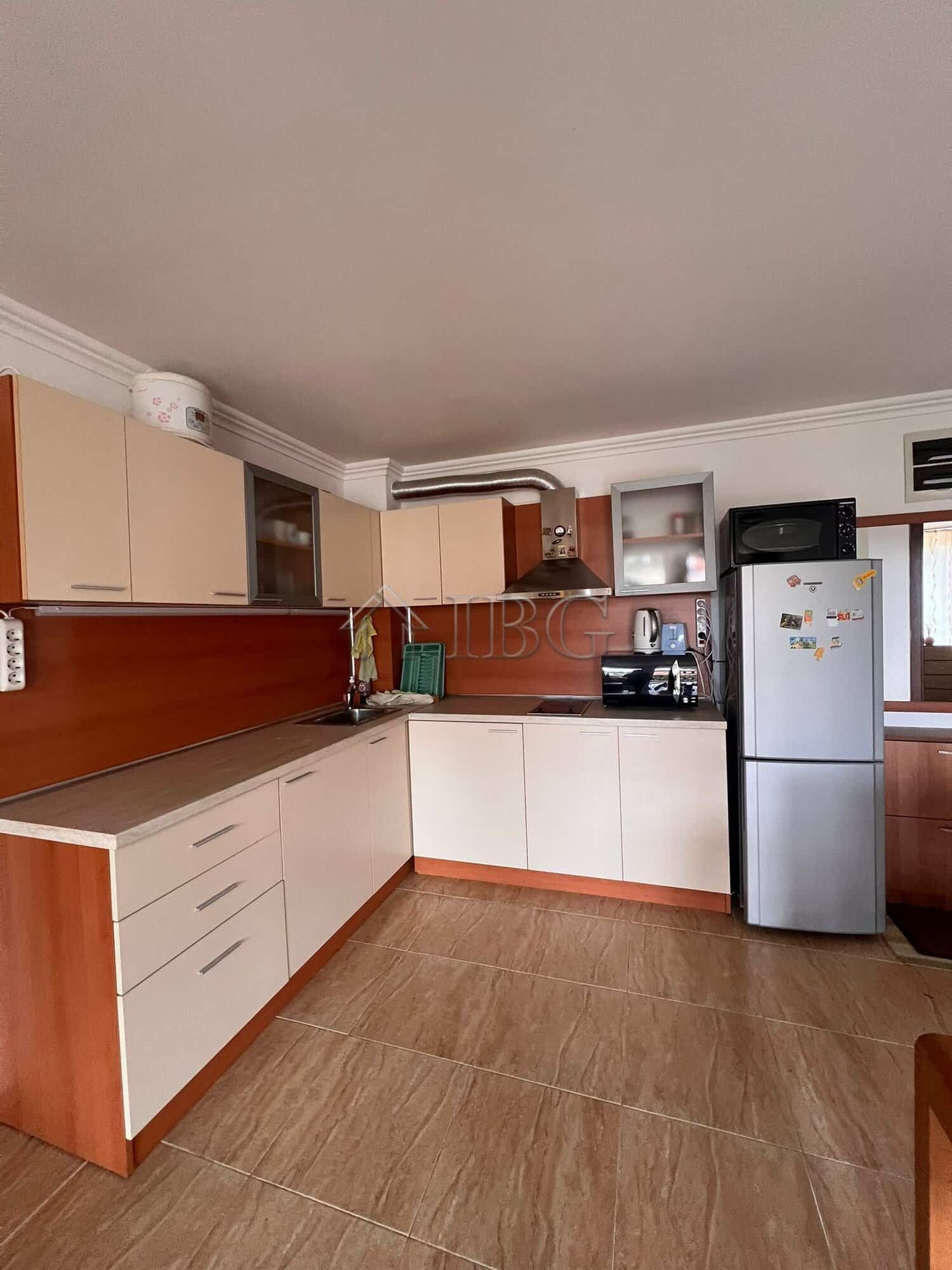Spacious kitchen with white and wood cabinets, refrigerator, and appliances in Sveti Vlas.