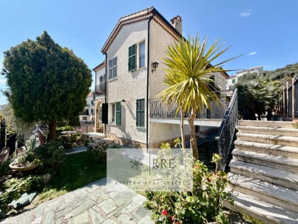Beautiful Mediterranean-style villa with lush garden and outdoor seating area.