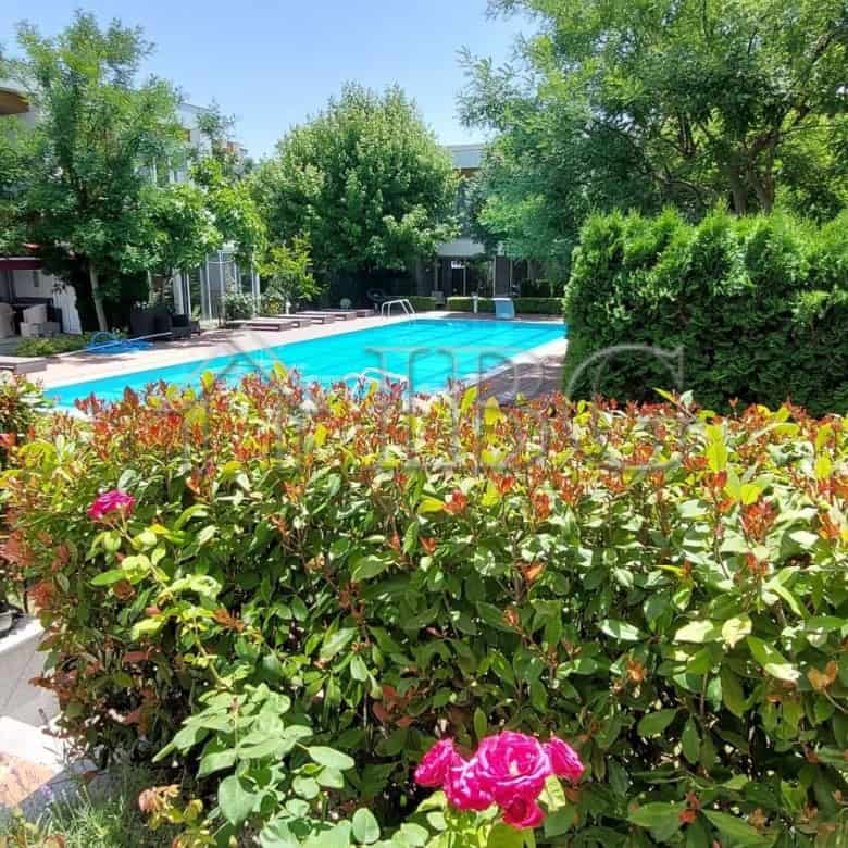 Bright outdoor pool area surrounded by lush greenery and colorful flowers in Sarafovo.