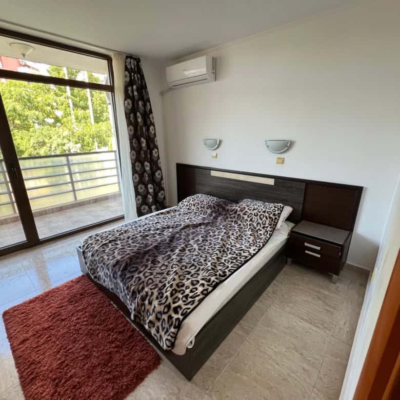 Comfortable bedroom with leopard print bedding and balcony view.