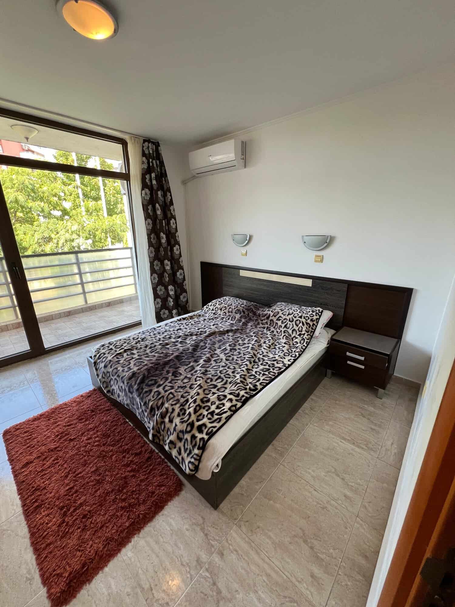 Comfortable bedroom with leopard print bedding and balcony view.