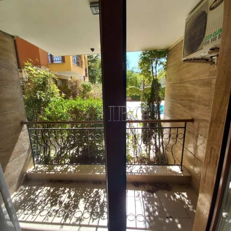 Bright apartment balcony overlooking pool and greenery.