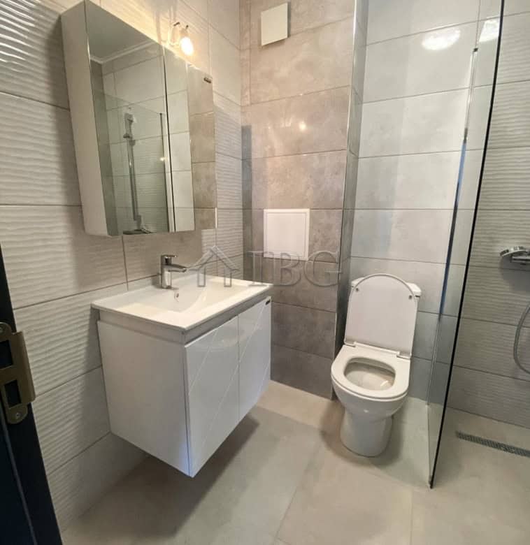 Modern bathroom with a sleek vanity, mirror, and toilet in a contemporary apartment.