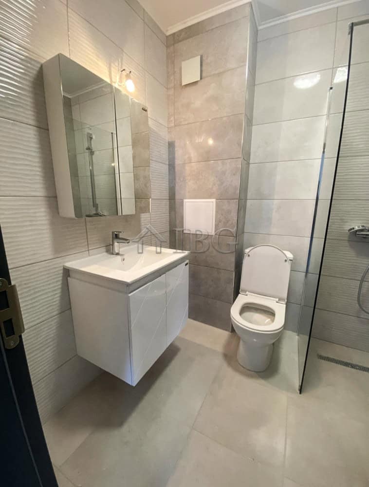 Modern bathroom with a sleek vanity, mirror, and toilet in a contemporary apartment.