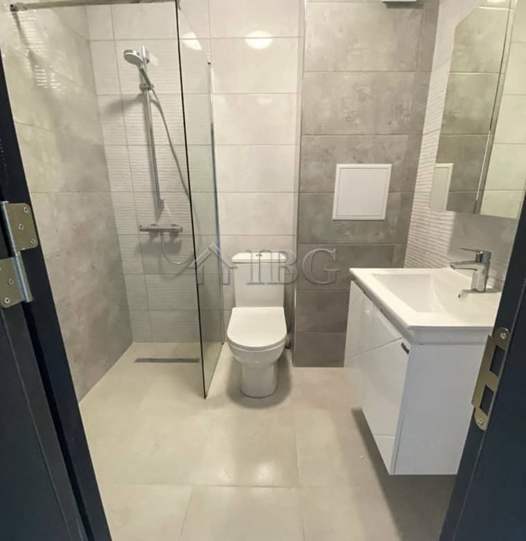 Bright bathroom with walk-in shower, toilet, and sleek vanity in a luxury apartment.