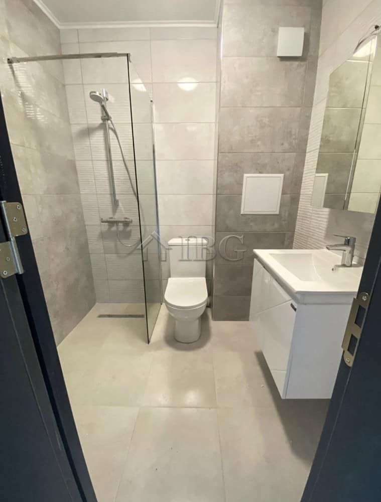 Bright bathroom with walk-in shower, toilet, and sleek vanity in a luxury apartment.