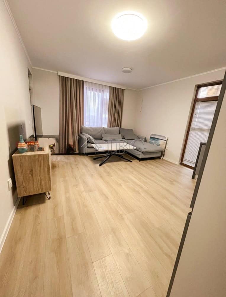 Bright living room with sofa and large window in a fully furnished 1-bedroom apartment.