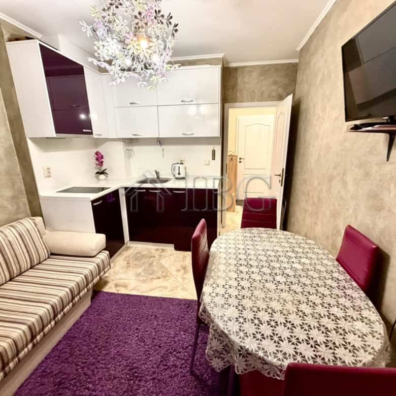 Bright interior of a one-bedroom apartment with modern furnishings and a small kitchen area.