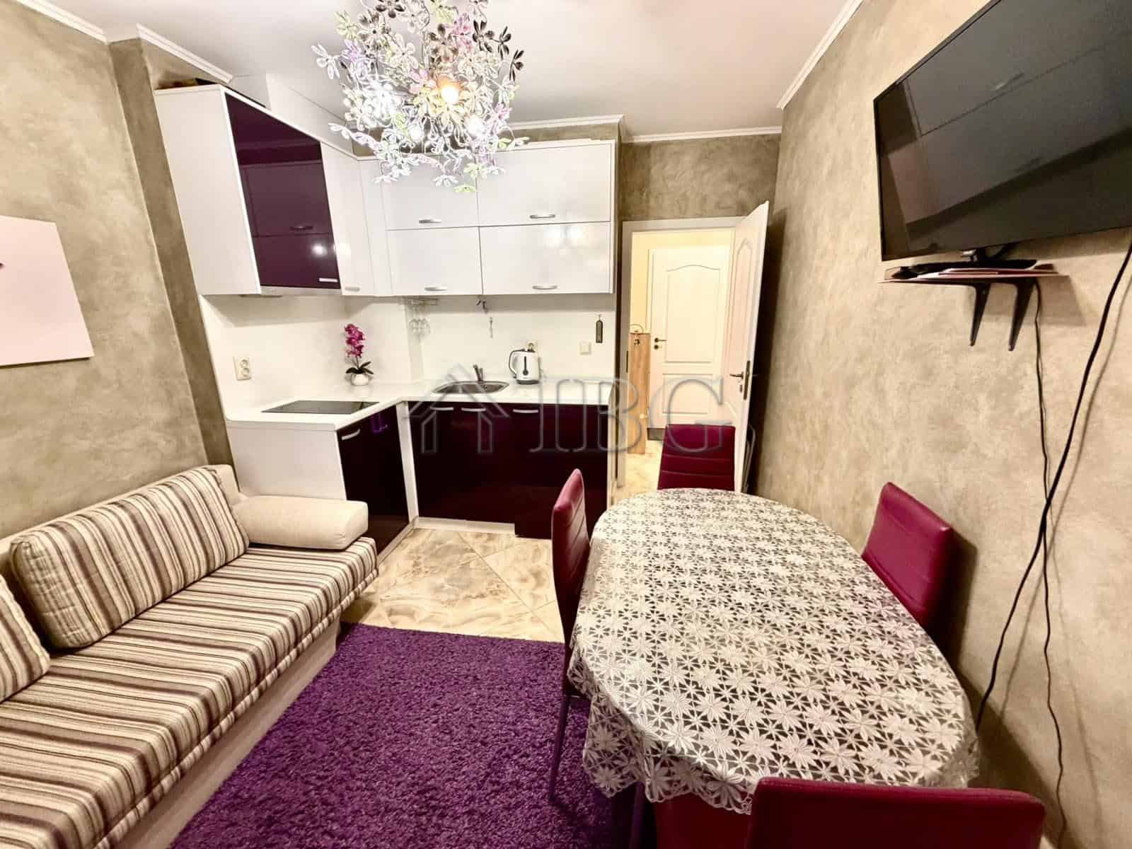 Bright interior of a one-bedroom apartment with modern furnishings and a small kitchen area.