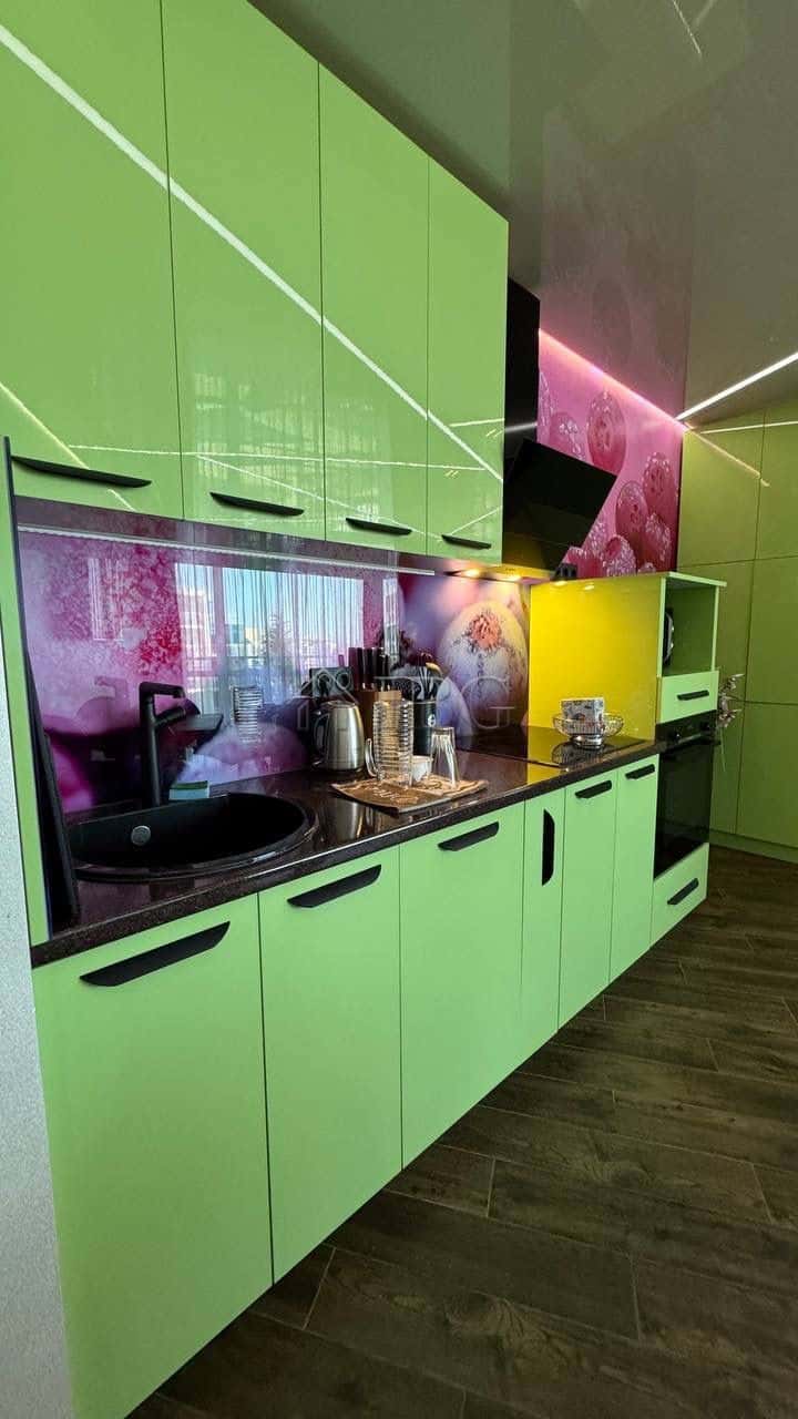 Bright green kitchen cabinets with black handles and vibrant pink and yellow accents.