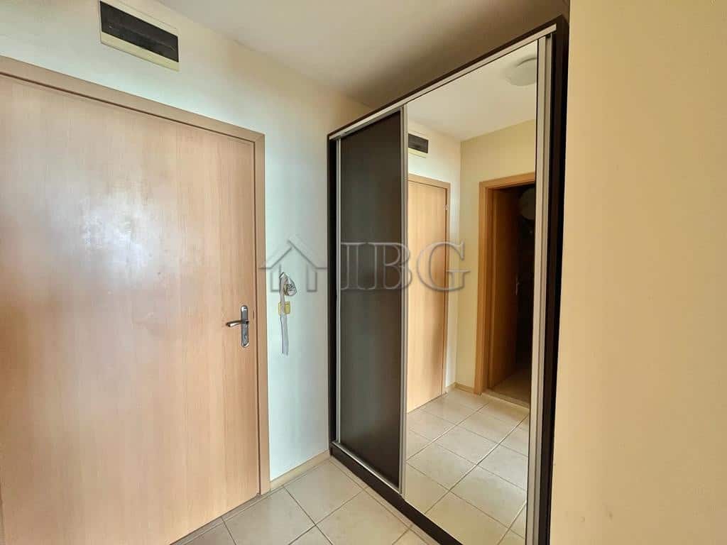 Modern beachfront home interior with wooden door and mirrored closet door.