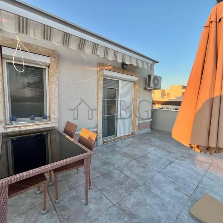 Terrace with outdoor dining table, chairs, and large umbrella overlooking the sea in Ravda.