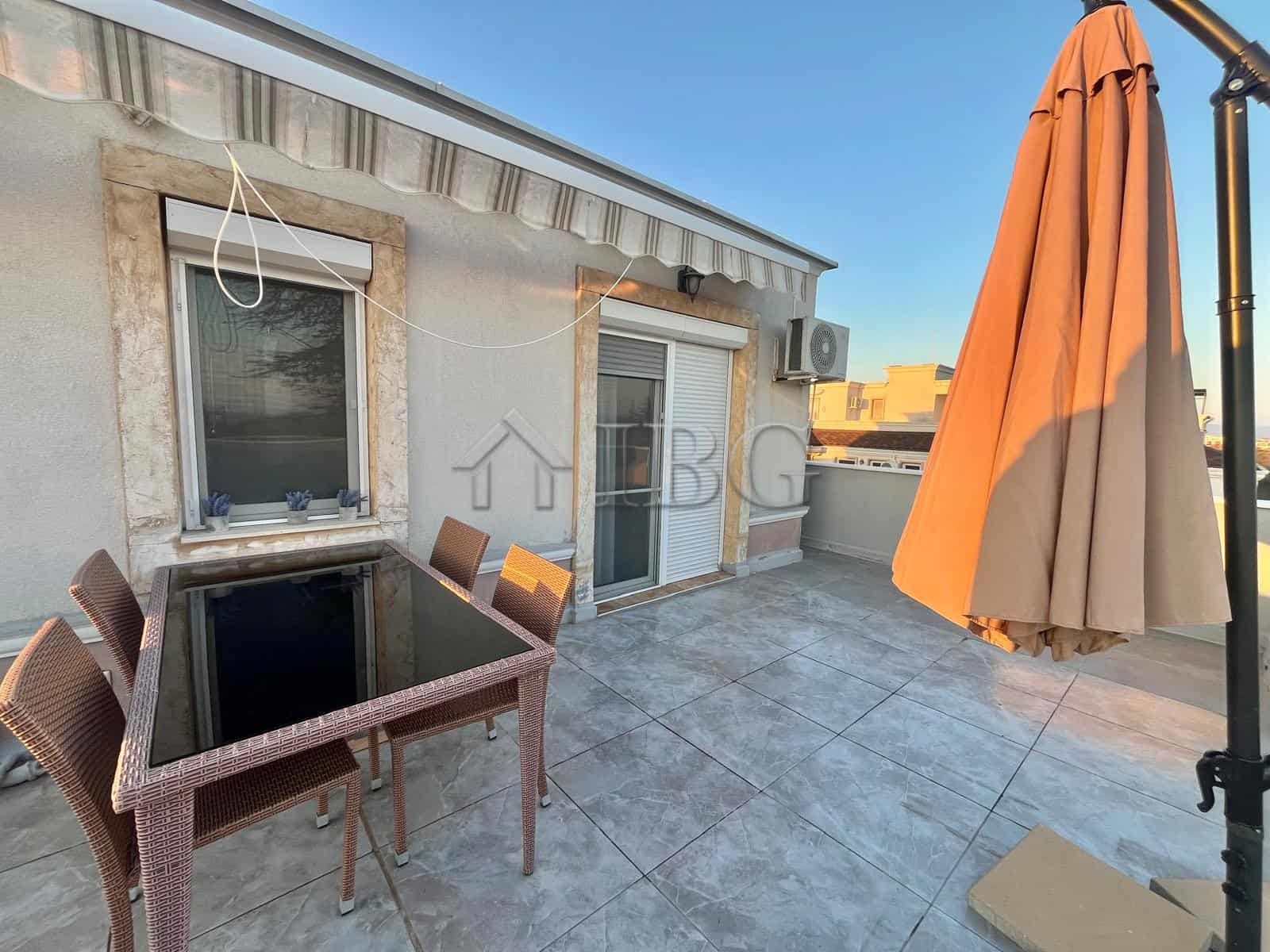 Terrace with outdoor dining table, chairs, and large umbrella overlooking the sea in Ravda.