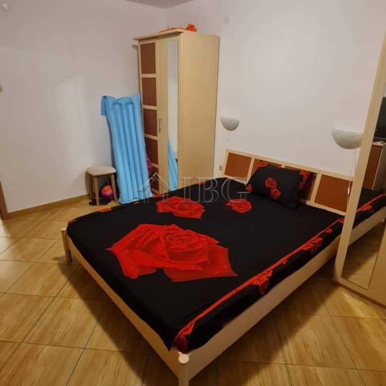 Interior of a bedroom in Sunny Beach apartment with bed, wardrobe, and blue chair.