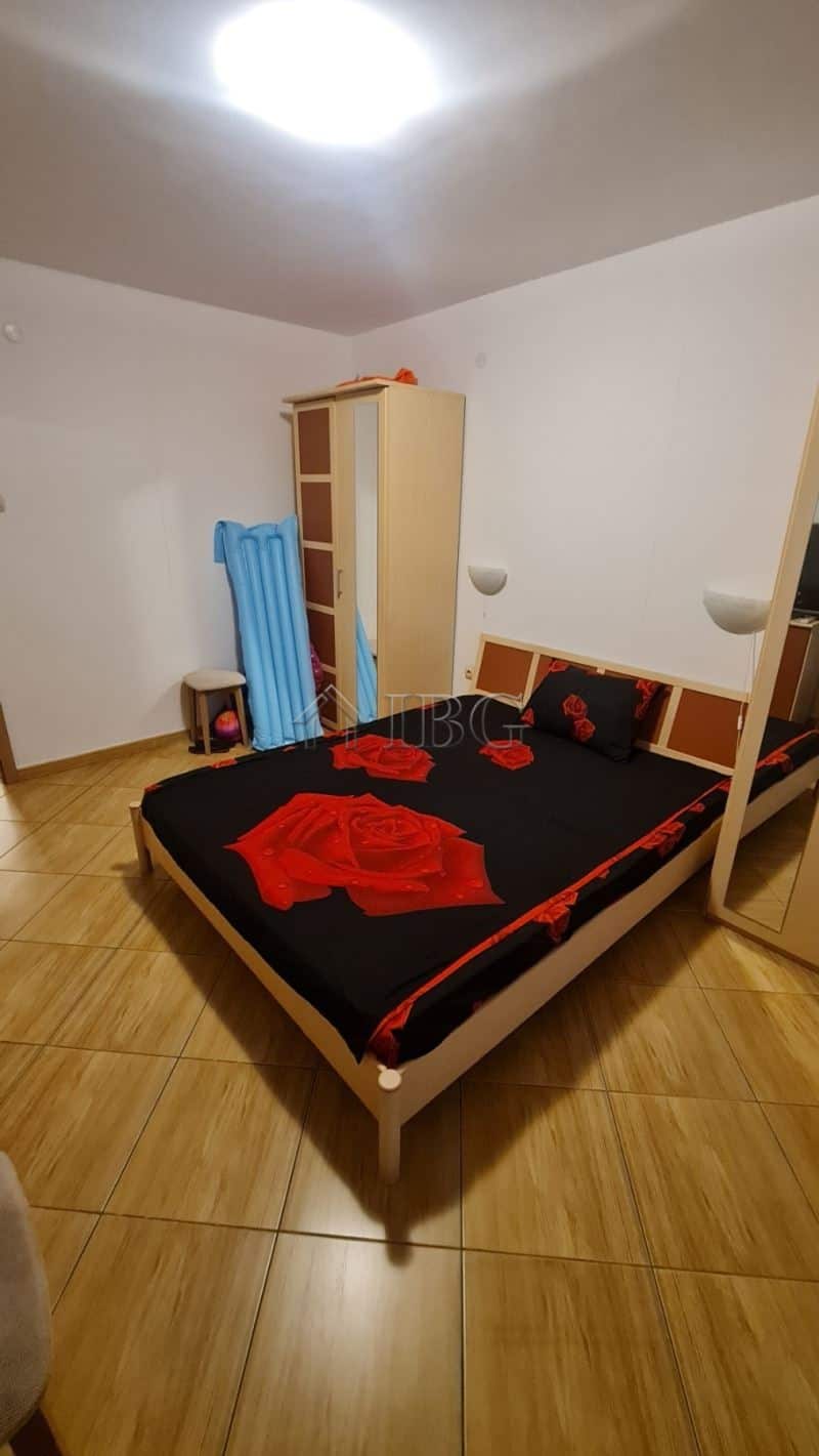 Interior of a bedroom in Sunny Beach apartment with bed, wardrobe, and blue chair.