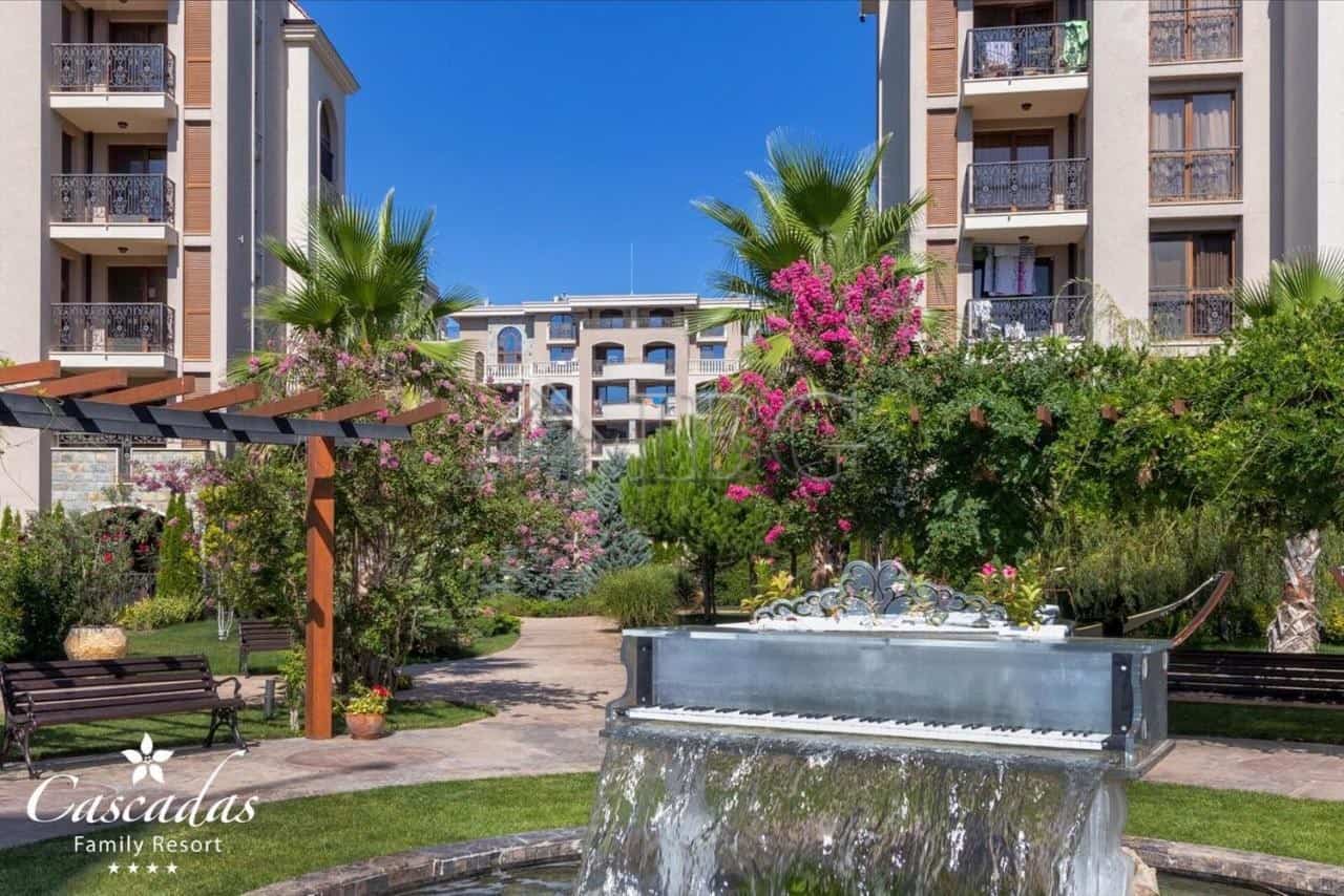 Beautiful garden view featuring a fountain, palm trees, and flowering bushes at Cascadas Family Reso.