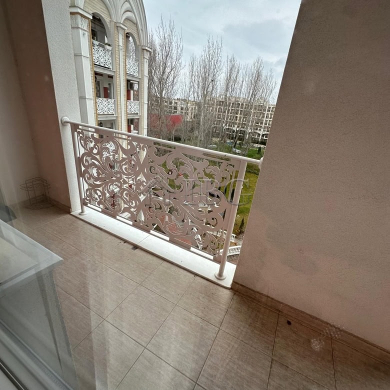 Balcony overlooking a cityscape with decorative railing and nearby buildings.