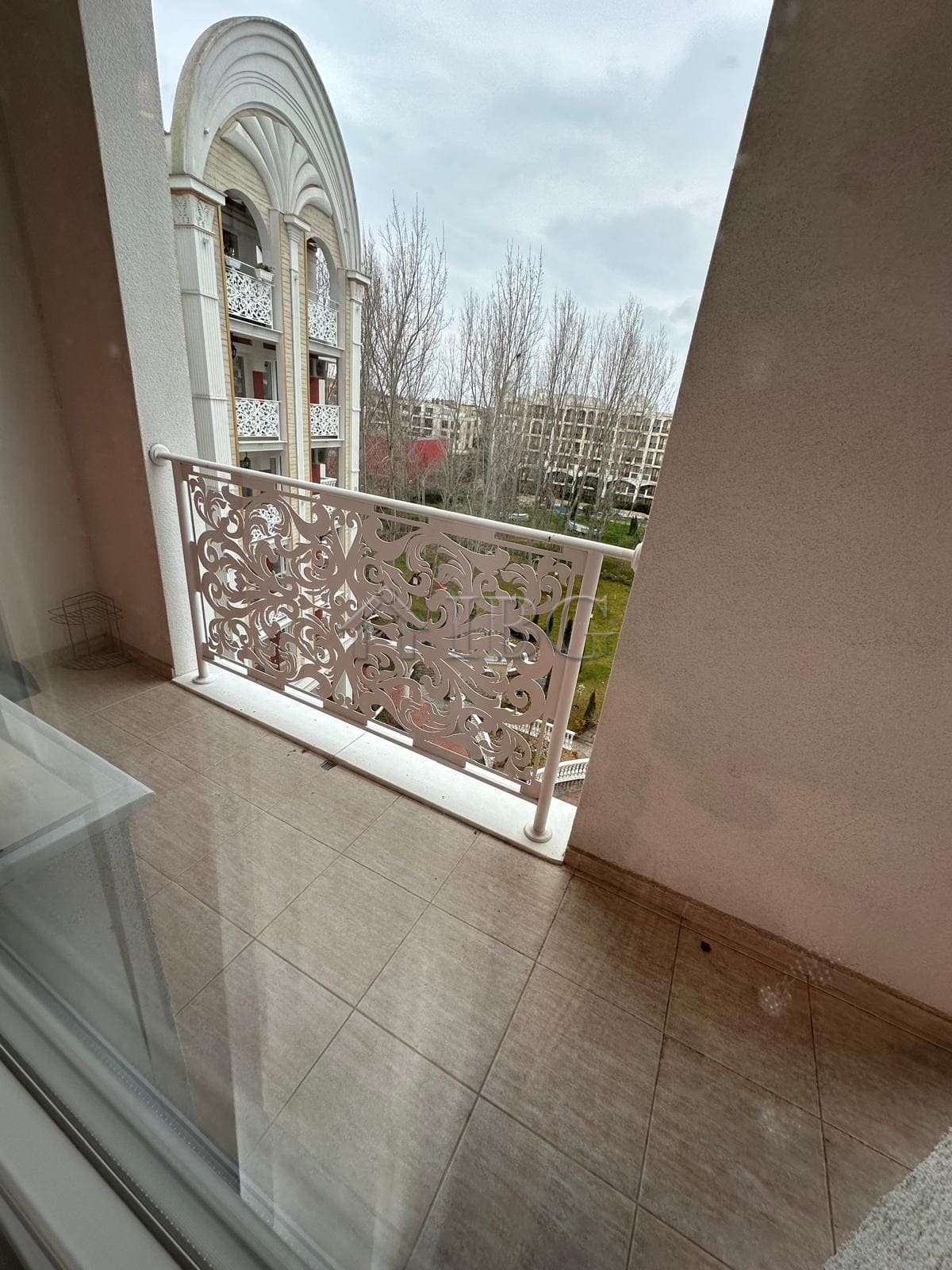 Balcony overlooking a cityscape with decorative railing and nearby buildings.