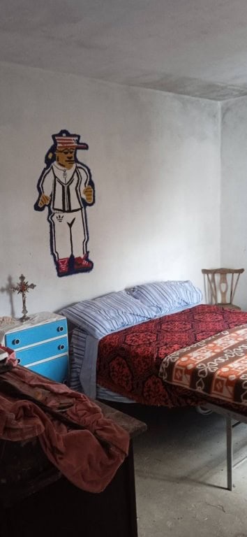 Interior of a rustic bedroom with a painted wall figure, simple furniture, and cozy bedding in a rur.