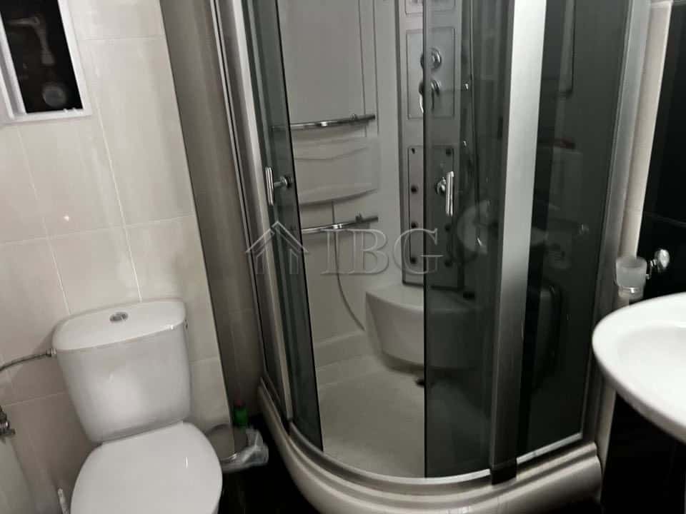 Bathroom with shower cabin, toilet, and sink in a seaside apartment.