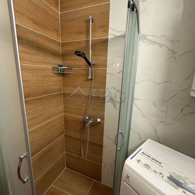 Compact shower area with wooden wall tiles and modern fixtures.