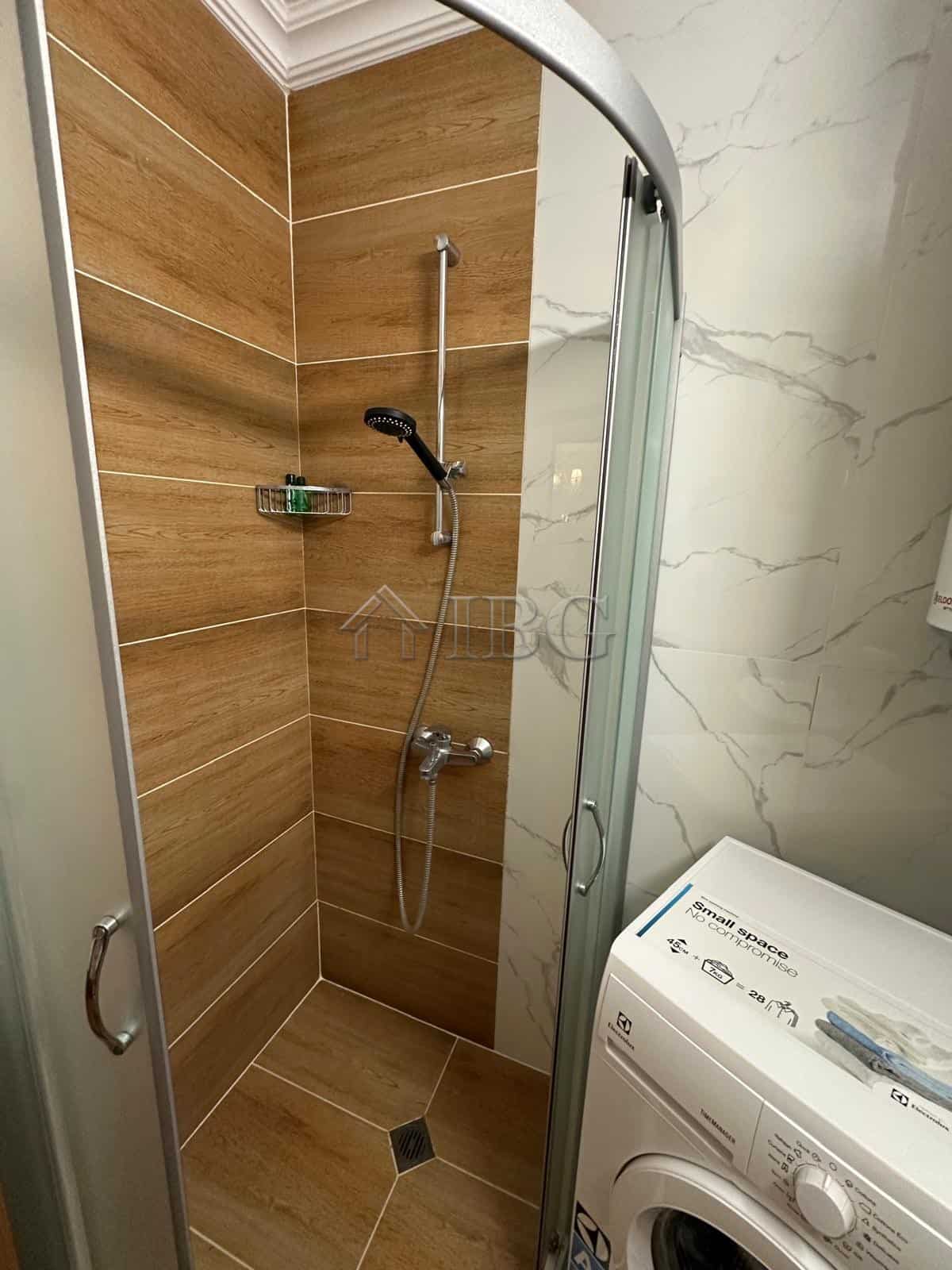 Compact shower area with wooden wall tiles and modern fixtures.