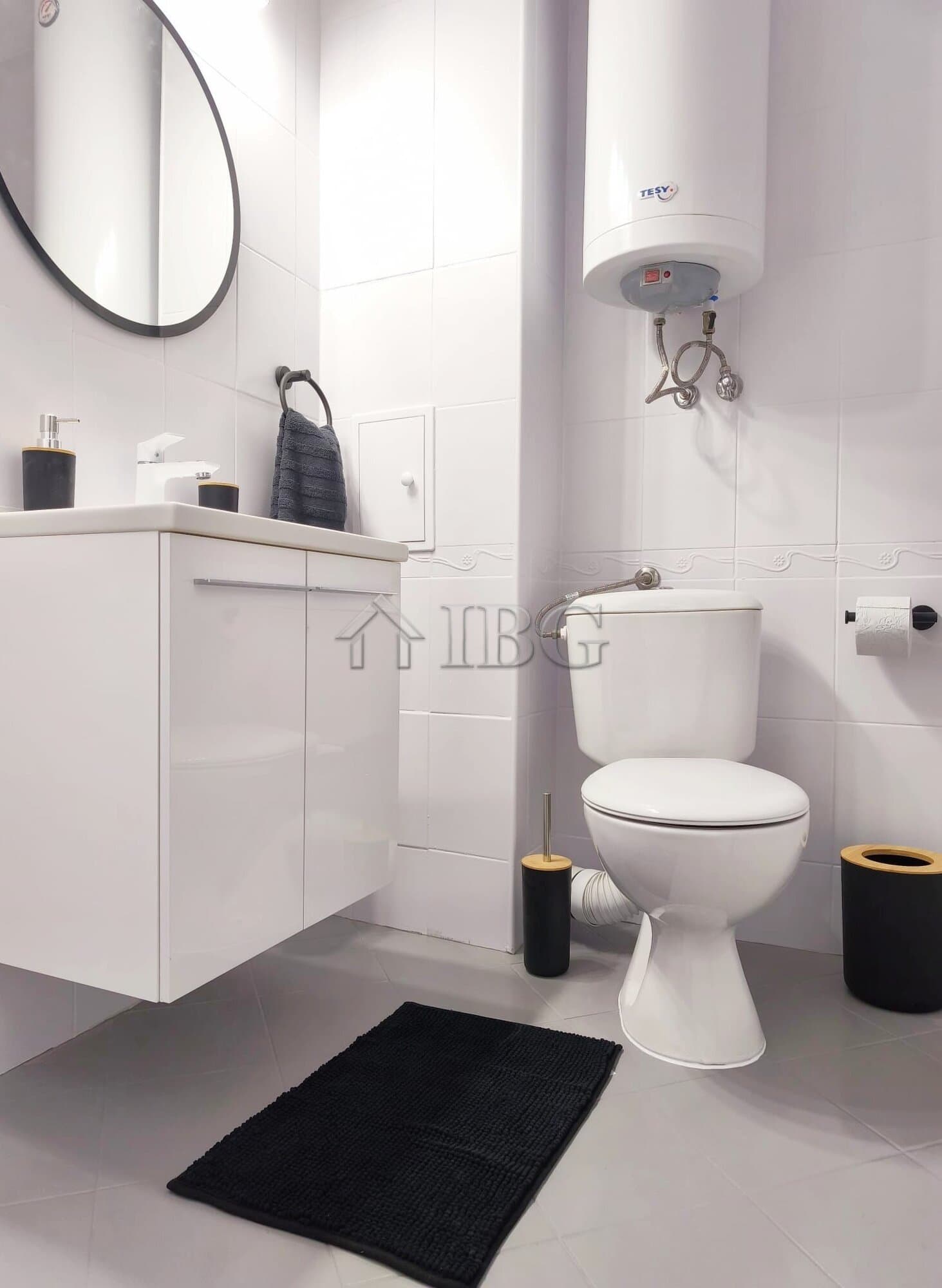 Cozy bathroom with modern fixtures, water heater, and black accessories in a stylish apartment.