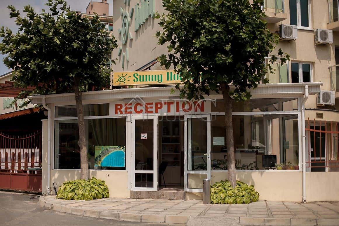 Reception area of Sunny Holiday hotel in Sunny Beach with glass doors and welcoming signage.