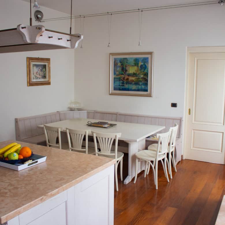 Bright dining room with white table and chairs, artwork on the wall, and wooden flooring.