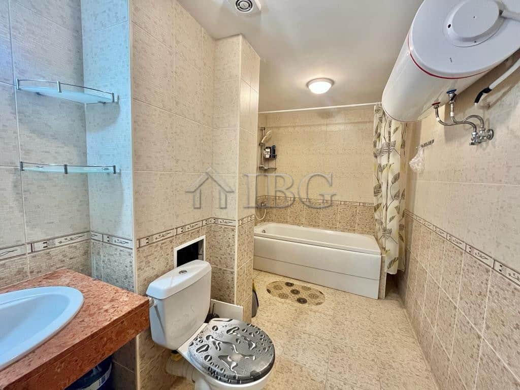 Spacious bathroom featuring a bathtub, water heater, and modern fixtures in a sunny beachfront prope.