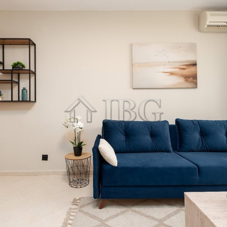 Modern living room featuring a blue sofa, wall art, and decorative shelves in a bright, airy space.