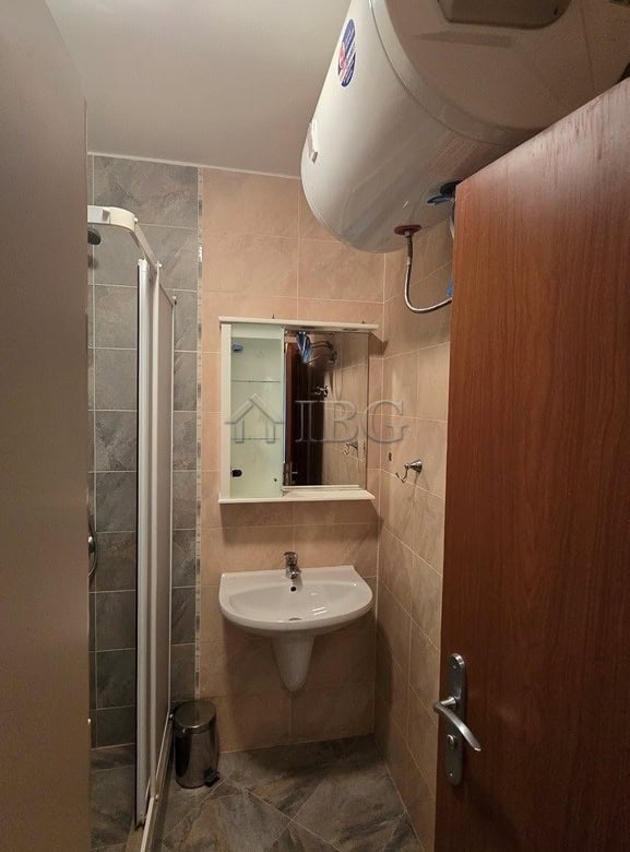 Bright bathroom in Sunny Beach apartment with shower, sink, and water heater.