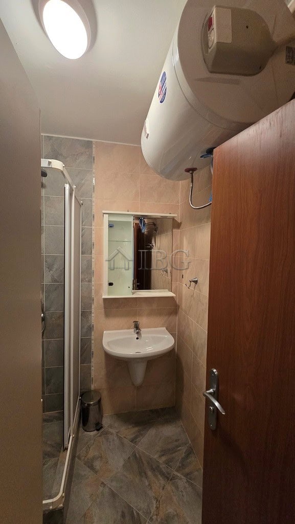 Bright bathroom in Sunny Beach apartment with shower, sink, and water heater.