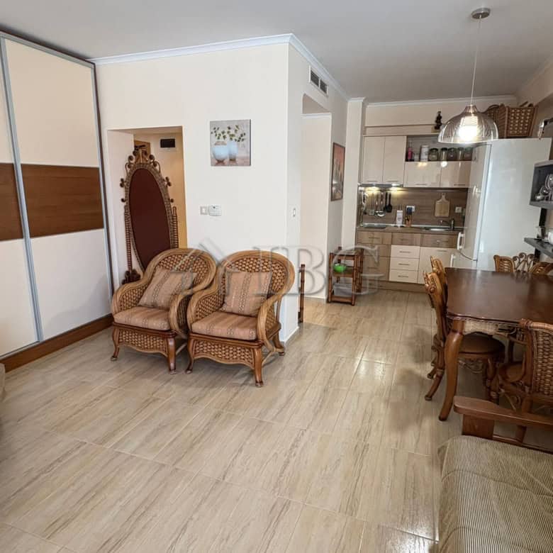 Bright living room with wicker chairs and dining area in a modern apartment.