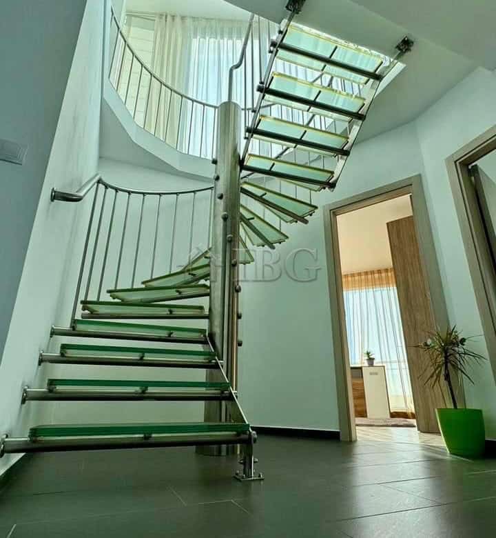 Spiral staircase inside a contemporary apartment with sleek design and metal railing.