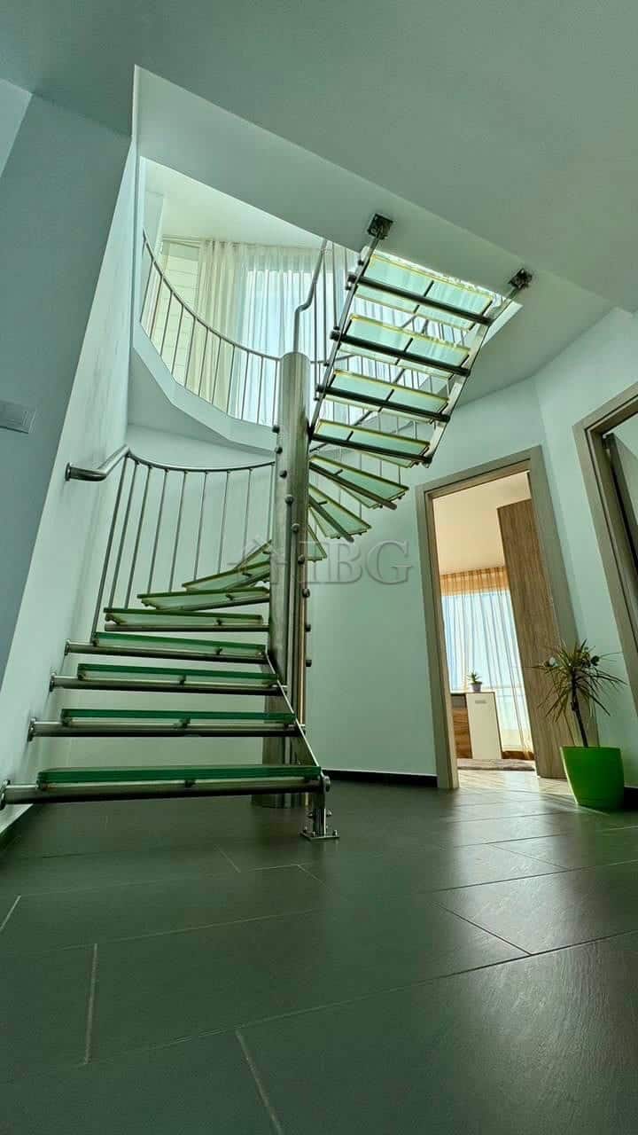 Spiral staircase inside a contemporary apartment with sleek design and metal railing.
