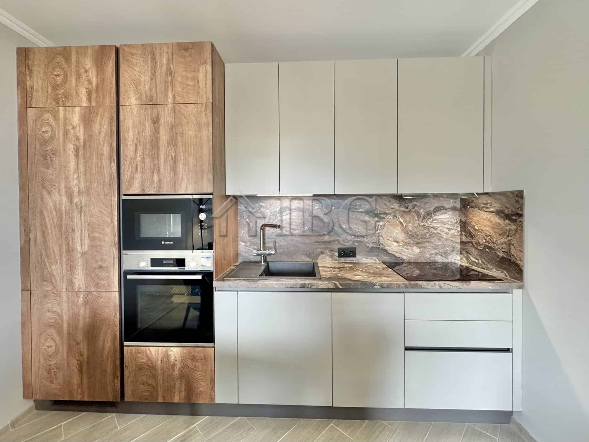Modern kitchen with wooden and white cabinetry, marble backsplash, and built-in appliances in Valenc.
