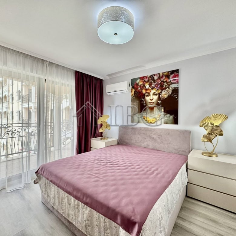 Bright bedroom featuring a large bed, elegant artwork, and access to a balcony with scenic views.
